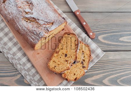 Homemade cake with dried apricots and raisins on wooden background.  