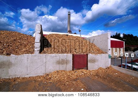 Bio Power Plant With Storage Of Wooden Fuel Against Blue Sky