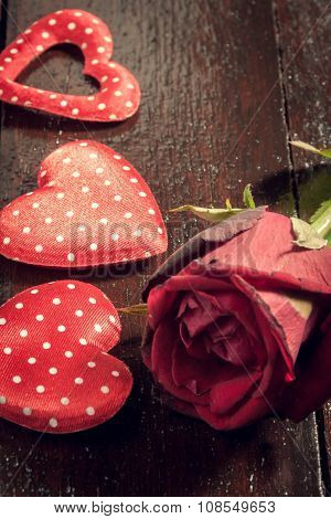 red rose and three heart shape on wood background.