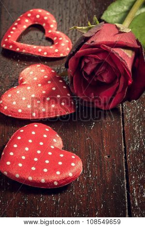 red rose and three heart shape on wood background.