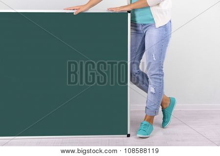 Woman in causal with green blackboard on grey background, close up