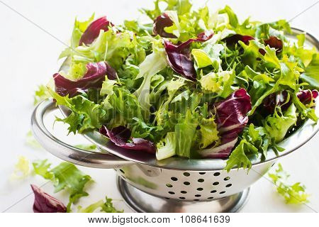 Fresh green salad wix in metal colander on white background