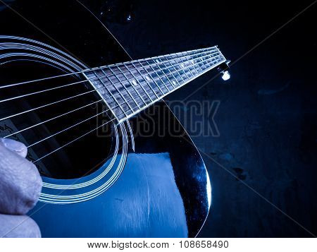 Closeup photo of an acoustic guitar played by a man.