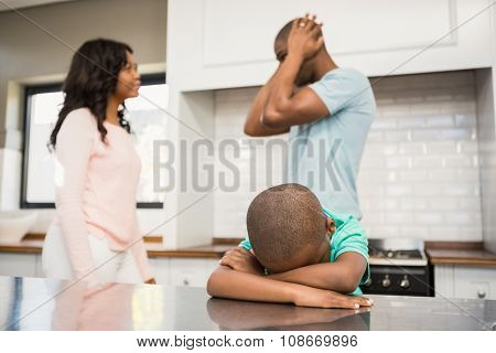 Mother and father arguing in the kitchen around their son