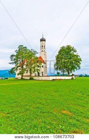 typical bavarian landscape with a chapel and green meadow