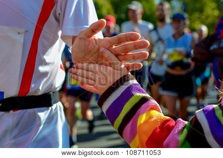 Marathon running race, support runners on road, child's hand giving highfive, sport concept