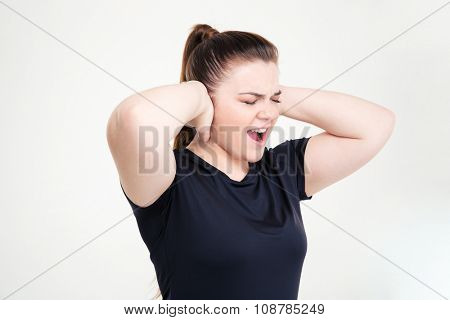Portrait of a fat woman in sportswear covering her ears and shouting isolated on a white background