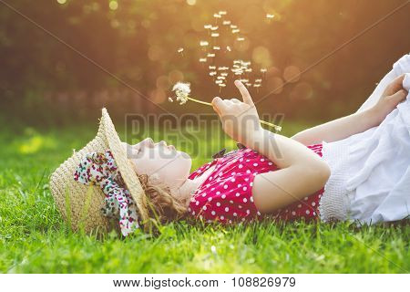 The Child Lays On A Grass And Blowing Dandelion In The Rays Of The Sun. Background Toning For Instag
