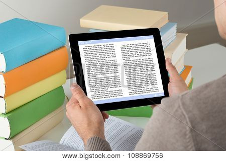 Student Holding Ereader While Studying At Desk