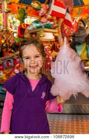 a girl has fun and look at a fairground. and eating cotton candy.
