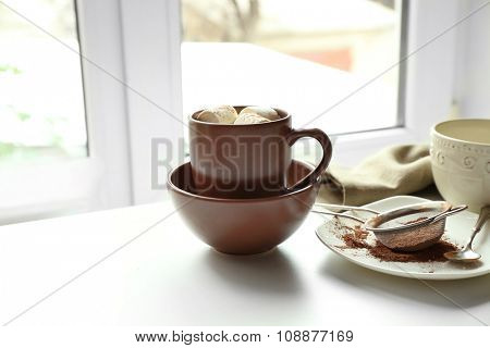 Cup of coffee with marsh mellow on a table in kitchen