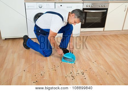 Janitor Sweeping Floor With Brush And Dustpan In Kitchen
