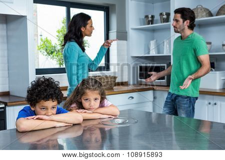 Sad children listening to parents argument in the kitchen