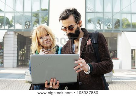 couple of young office mates with laptop computer outside office
