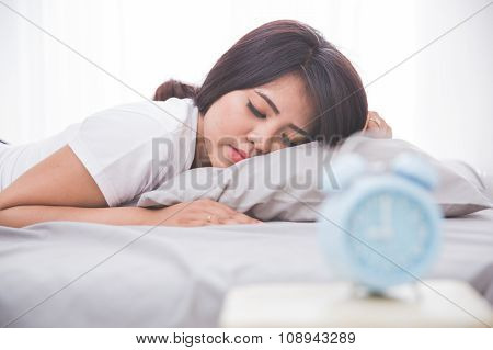Alarm Clock In Front Woman Sleeping On A Bed