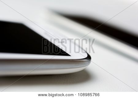 A White Mobile And A Silver Smartphone Lying On White Leather
