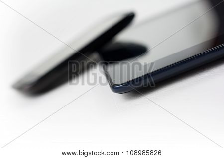 Black Smartphone Leaning On A Black Tablet With Reflection