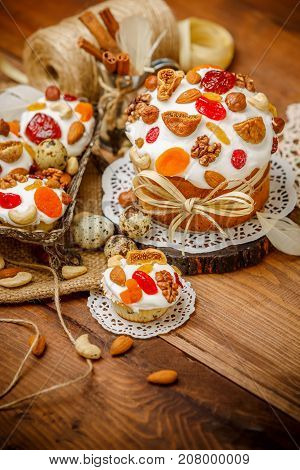 Traditional Easter cake with decorations and cupcakes on wooden table