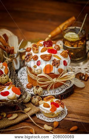 Traditional Easter cake with decorations and cupcakes on wooden table