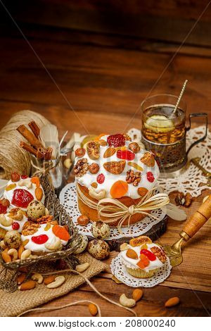 Traditional Easter cake with decorations and cupcakes on wooden table