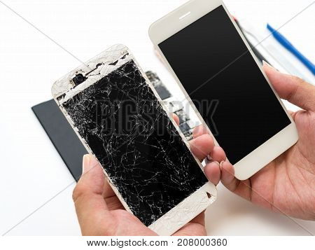 Close-up of cracked smartphone screen compare with new screen in technician hand on blurred smartphone component background