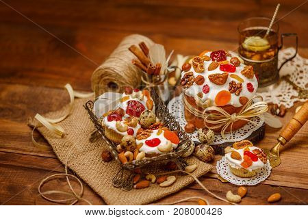 Traditional Easter cake with decorations and cupcakes on wooden table