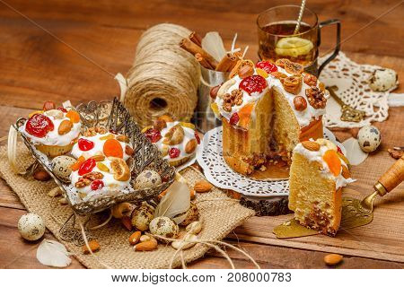 Traditional Easter cake with decorations and cupcakes on wooden table