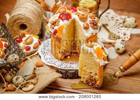 Traditional Easter cake with decorations and cupcakes on wooden table