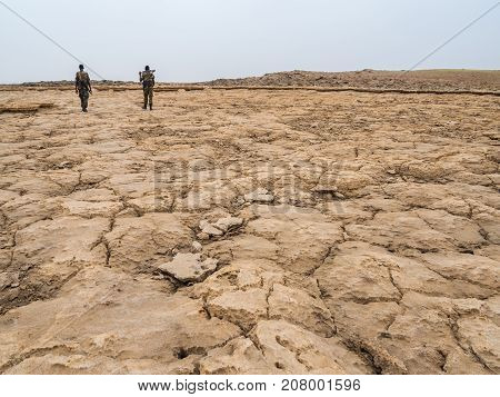 People walking across mineral soil formations around lake Dallol in Danakil Depression Ehtiopia