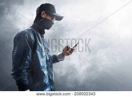 Hacker using mobile phone on smoke background