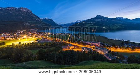 Night panorama of Lake Lucerne. Mountain range snow on the tops of the mountains. Axenstrasse. Lights in the houses and along the road. Switzerland Alps.