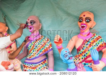 Artist preparing clay idols of female demons to be used during Kali Puja worshipping of Goddess Kali at Kumartuli - Kolkata India. Hindu festival of Deepavali or Diwali.