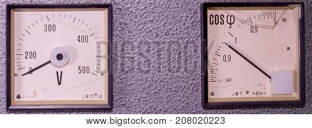 Two old analog instruments - Power factor meter  and voltmeter isolated on grey background