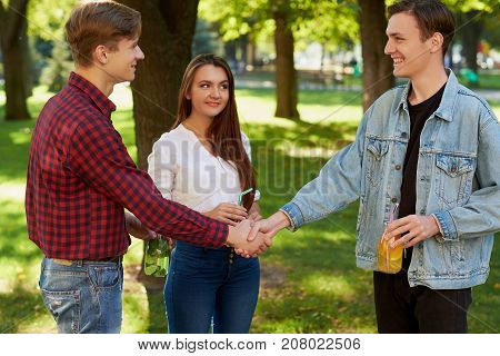 Meeting with old friend concept. Cheerful young people with detox cocktail looking happy while having outdoor summer party