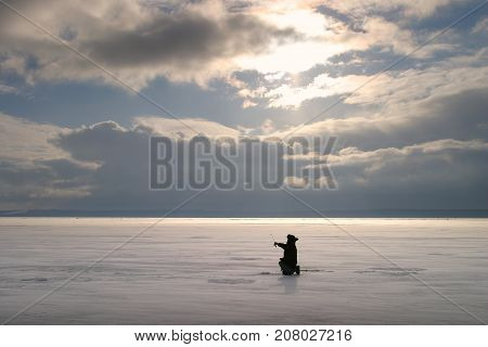 Fisherman On The River Covered With Ice