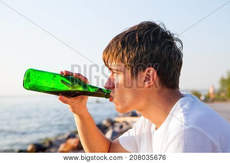 Young Man drink a Beer on the Seaside Background