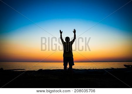 Man Silhouette Praying at the Sunset on the Sea Background
