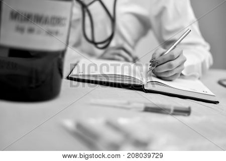 A stethoscope in the hands of the doctor black and white poster