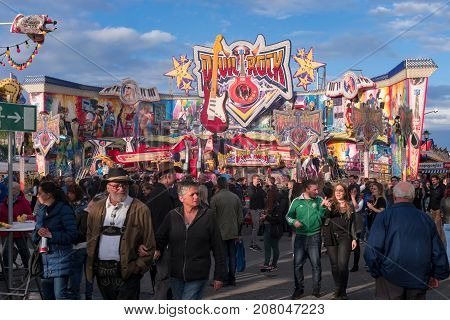 An older couple at the wine festival or carnival surrounded by a crowd of people in front of the colorful attractions. Bad-Duerkheim, Germany - September 16 2017.