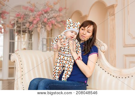 happy mother holding her baby and playing with him indoors