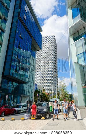 TIRANA ALBANIA - SEPTEMBER 6 2017: Modern high-rise buildings (Eurocol Business Center Toptani shopping center Hotel Plaza). Unknown young people are walking down Street Murat Toptani