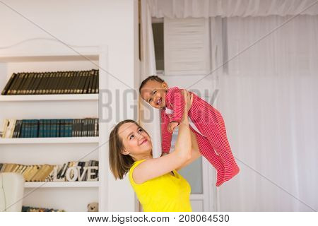 happy family. Mother throws up baby, playing at home.