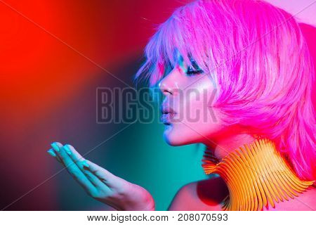 High Fashion model woman portrait in colorful bright lights, beautiful party girl with trendy make-up, manicure, haircut. Pointing hand, advertising gesture over colourful vivid background.