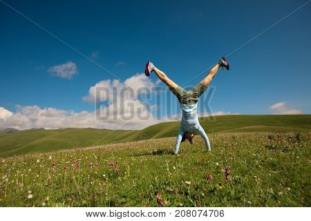 woman doing a handstand in a mountain peak meadow