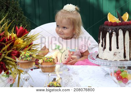 Girl birthday. A little white-haired girl of two years is trying a birthday cake. Little girl celebrating second birthday.