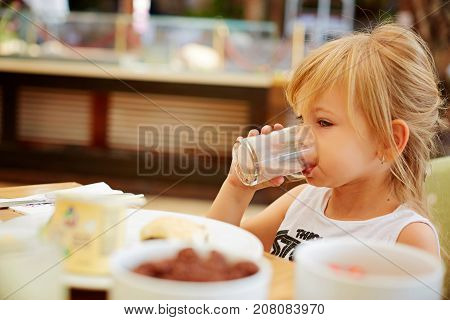 Little girl eating creme filled cookies while drinking a glass of milk.