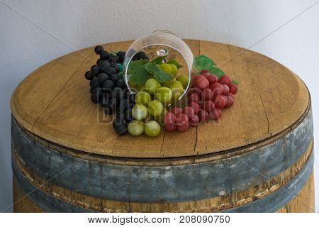 Glass and red white rose grapes and on old oak barrel