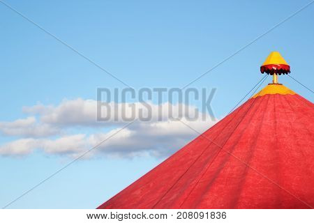 Red circus tent under the blue sky with beautiful clouds