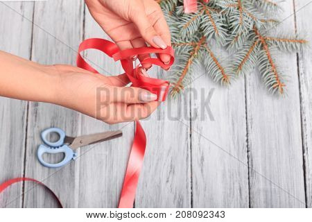 Red ribbon from which make a bow. Close-up. Next to it is a branch of spruce and blue scissors.