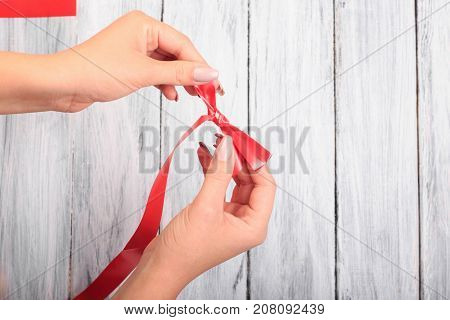 Red ribbon, from which make a bow. Close-up. On a gray background.